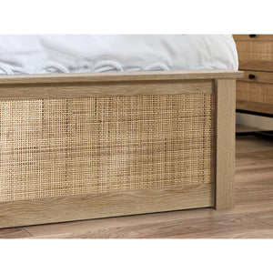 Wooden bed frame with wicker detailing on a wooden floor.