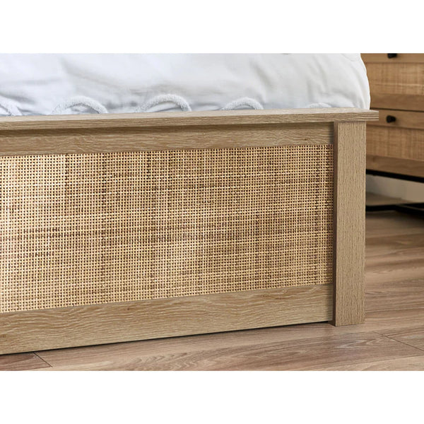 Wooden bed frame with wicker detailing on a wooden floor.