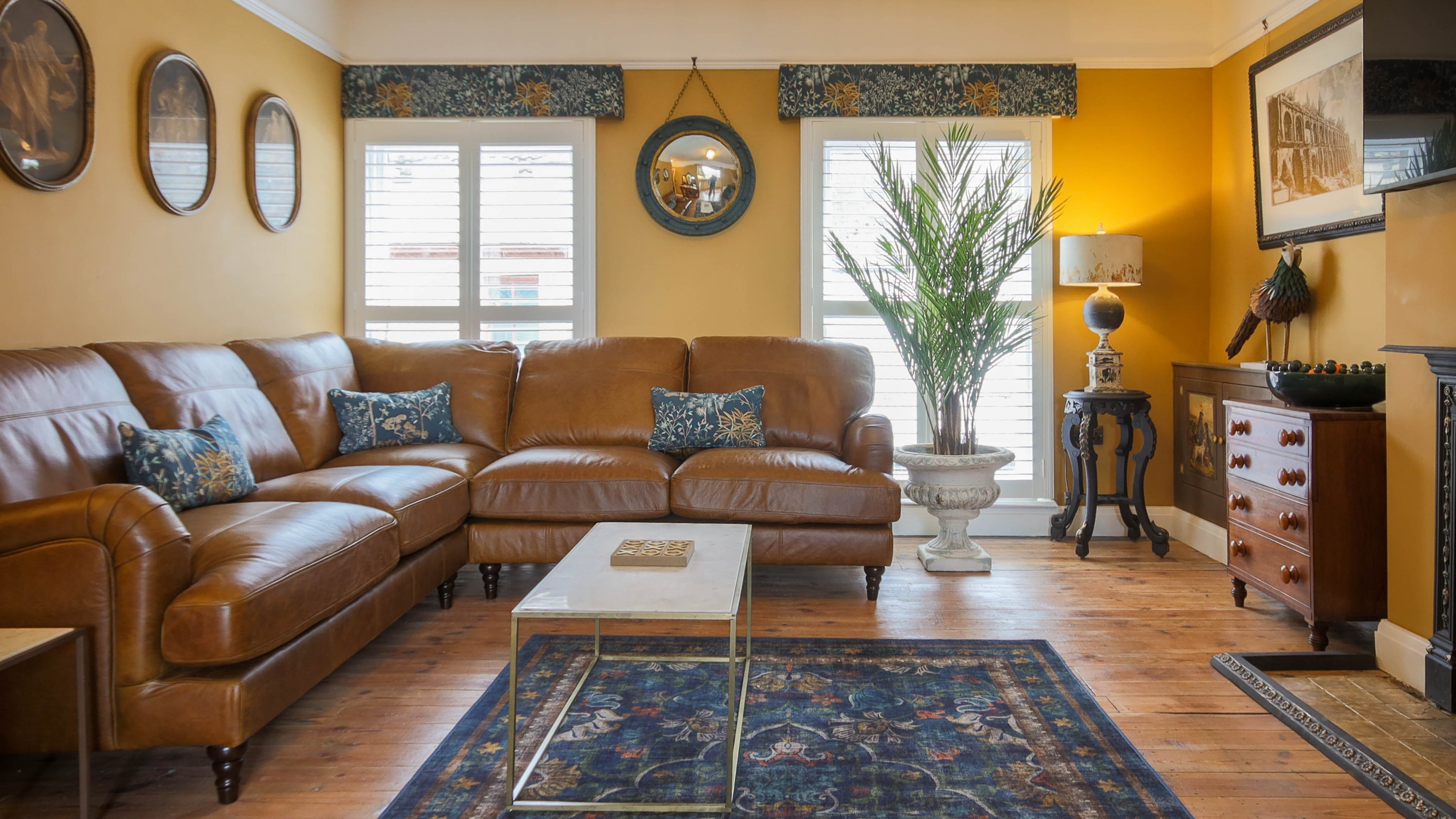 Living room with brown leather sectional sofa, coffee table, and decorative elements.