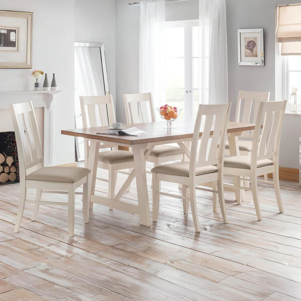 Dining room with a wooden table and white chairs on a wooden floor.