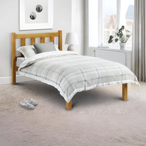 Bedroom with a wooden bed frame and gray bedding, featuring a window and plant.