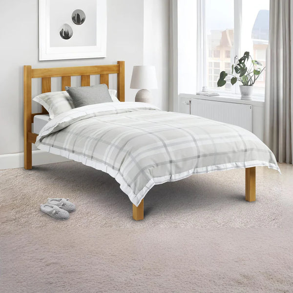 Bedroom with a wooden bed frame and gray bedding, featuring a window and plant.