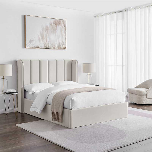 Beige upholstered bed in a modern bedroom with lamps and a sofa.