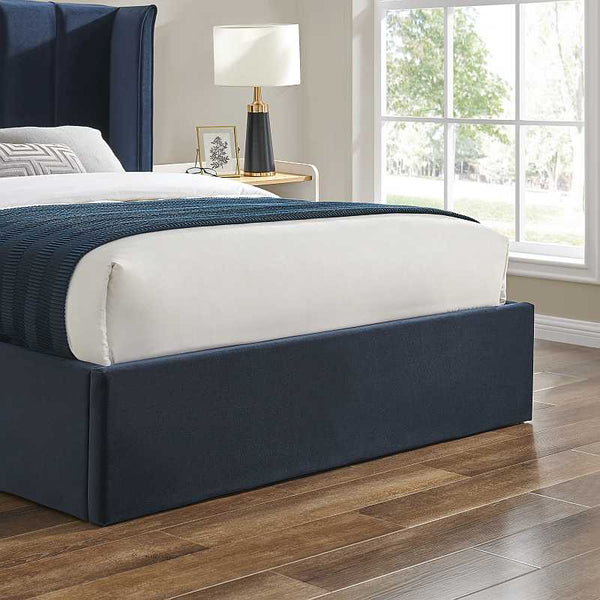 Bedroom with a bed featuring a navy headboard and bedding, a lamp on a nightstand, and a window.