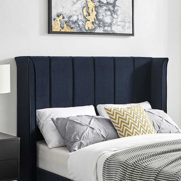 Navy blue upholstered headboard with decorative pillows in a bedroom setting.