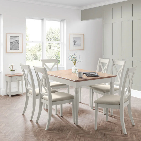Dining room with a wooden table and white chairs in a bright room.