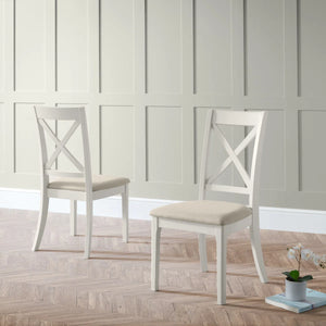 Two white chairs with beige cushions on a wooden floor against a paneled wall.
