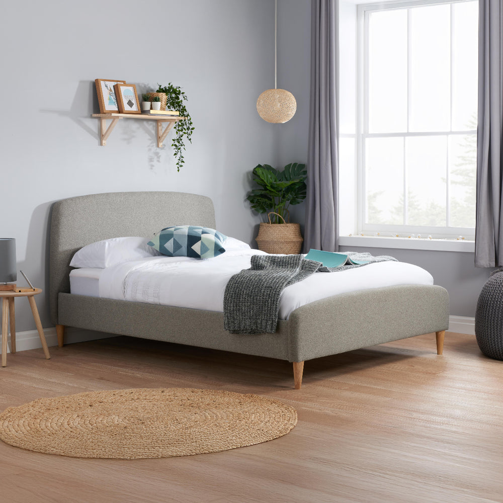 Gray upholstered bed with a mattress on a white background
