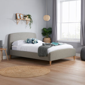 Neatly made bed in a bedroom with a window and decorative items.