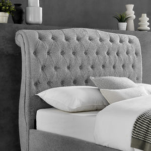 Gray tufted headboard with white pillows against a dark gray wall.