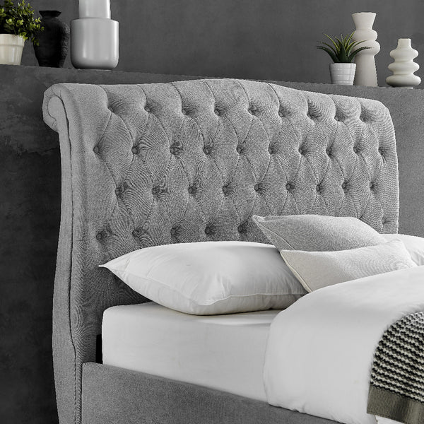 Gray tufted headboard with white pillows against a dark gray wall.