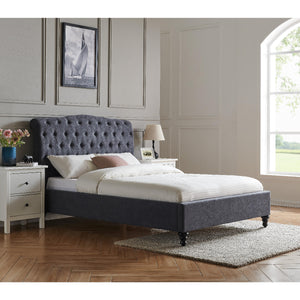 Gray upholstered bed in a bedroom with white walls and a window.