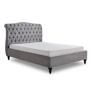 Gray tufted bed with white mattress on a white background