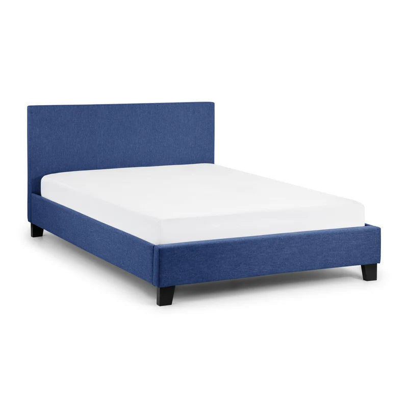 Blue upholstered bed with white mattress on a light gray background