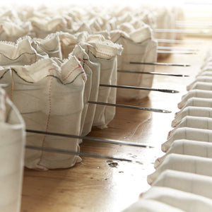 Close-up of white fabric pocket springs with stitching on a wooden surface