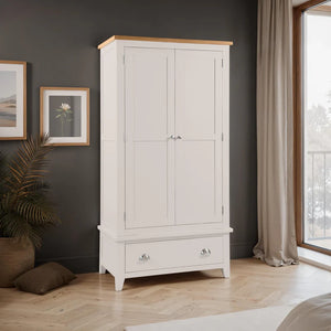 Grey wardrobe with wooden top in a room with dark walls, framed pictures, and a window.