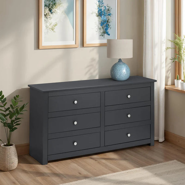 Gray dresser with white knobs in a room with framed artwork and a lamp.