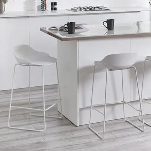 White bar stools in front of a kitchen island with a stove and counter.