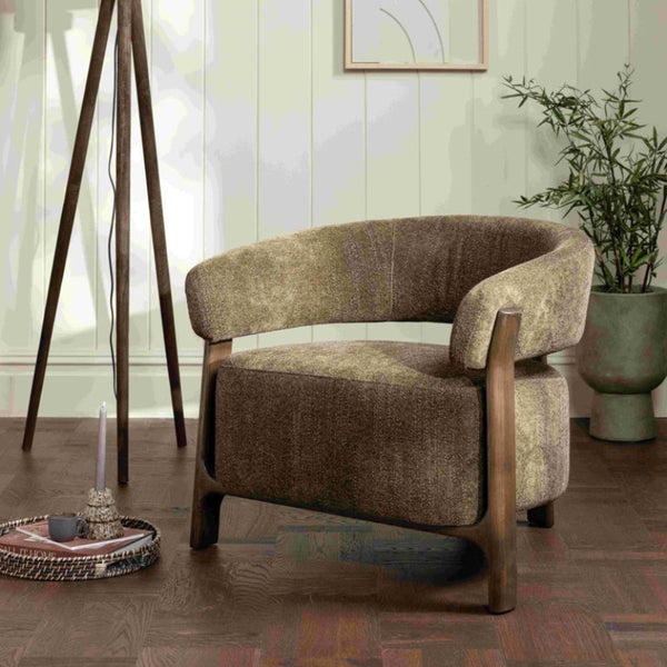 Brown armchair in a room with a lamp, plant, and abstract art on the wall.