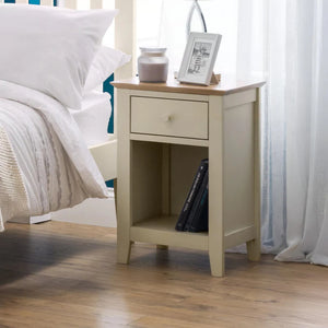Beige nightstand with a drawer next to a bed in a bedroom setting