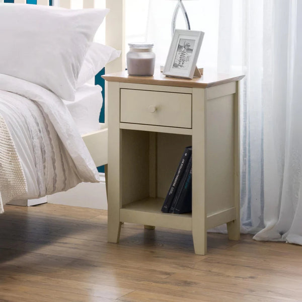 Beige nightstand with a drawer next to a bed in a bedroom setting
