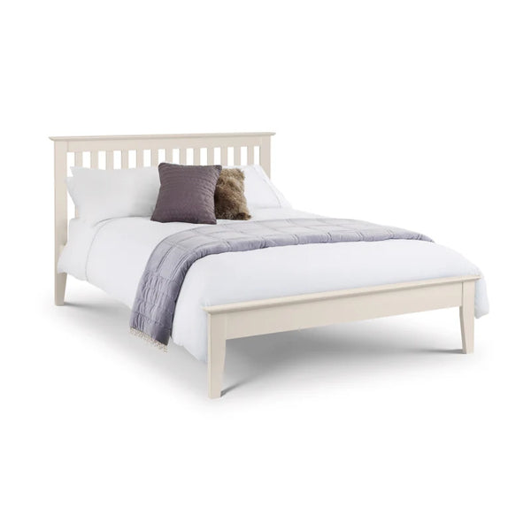White bed with white bedding and a purple pillow on a white background