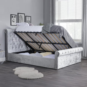 Gray upholstered bed with adjustable headboard in a room with a window and decor.