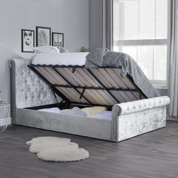 Gray upholstered bed with adjustable headboard in a room with a window and decor.