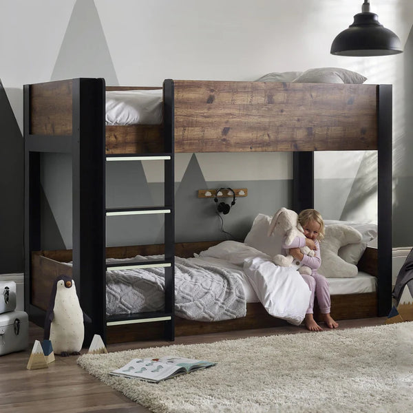 Child playing on a wooden bunk bed in a room with geometric wall design.