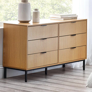 Wooden dresser with slatted design in a room with a window and decor items.