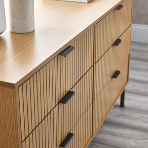 Wooden dresser with black handles on a wooden floor.