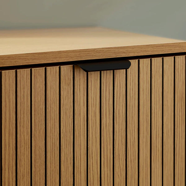 Wooden cabinet with a light brown finish and black handle on a neutral background