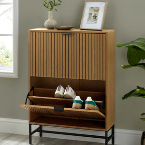 Wooden shoe cabinet with open door showing shoes, placed against a wall with a plant and framed picture.
