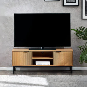 Wooden TV stand with a television on top in a room with a gray wall and plant.