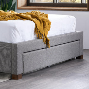 Gray upholstered bed with white mattress and yellow blanket in a room with a window.