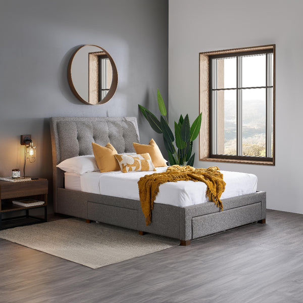 Gray upholstered bed with white bedding and yellow throw in a modern bedroom.