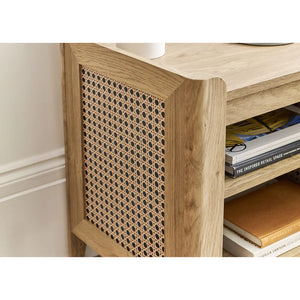 Wooden side table with rattan sides and books on a white background