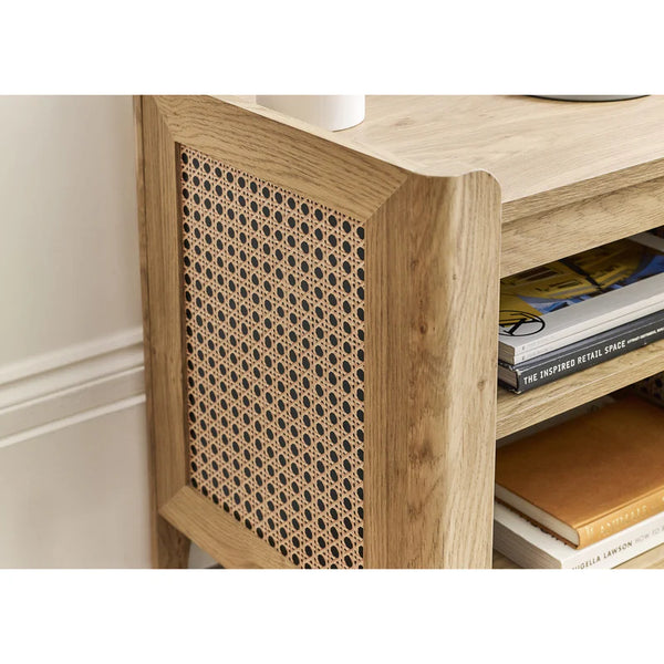 Wooden side table with rattan sides and books on a white background