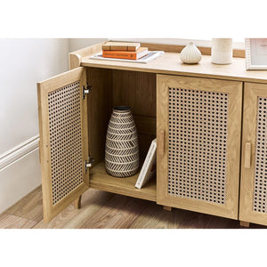 Wooden cabinet with wicker doors containing decorative items on a wooden floor.