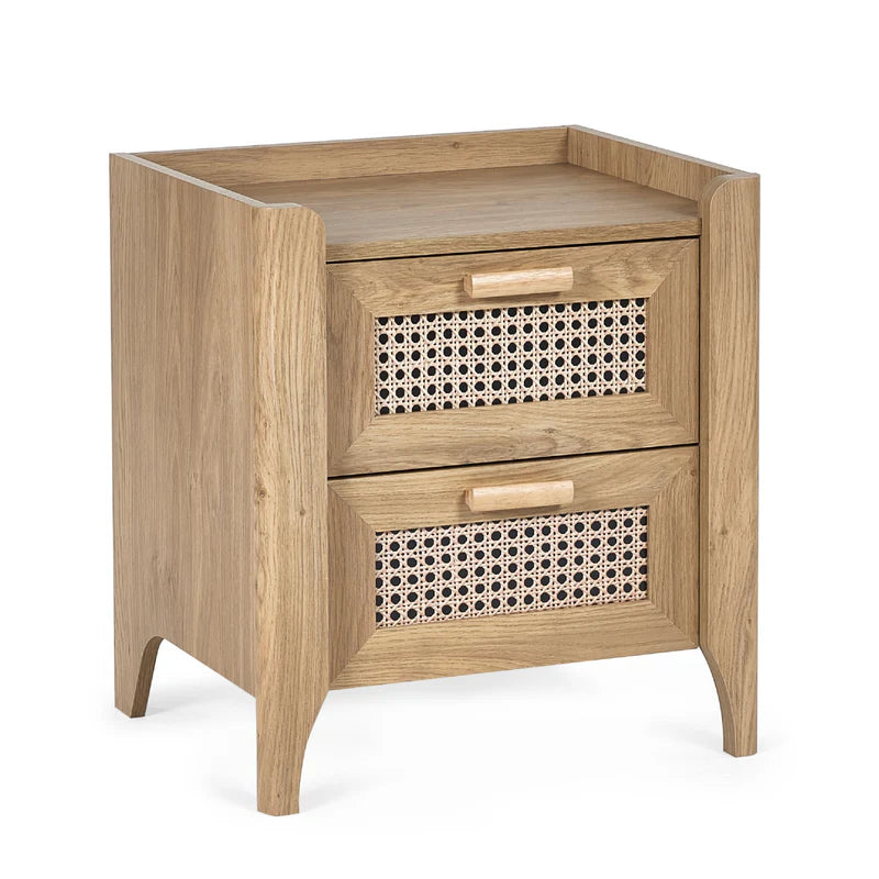 Wooden side table with two drawers and a cup on top in a room setting.