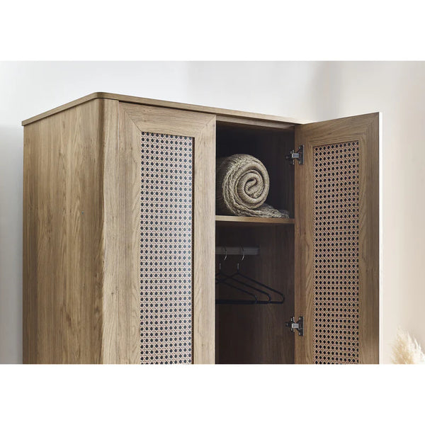 Wooden wardrobe with open doors showing a rolled-up towel and hangers inside.