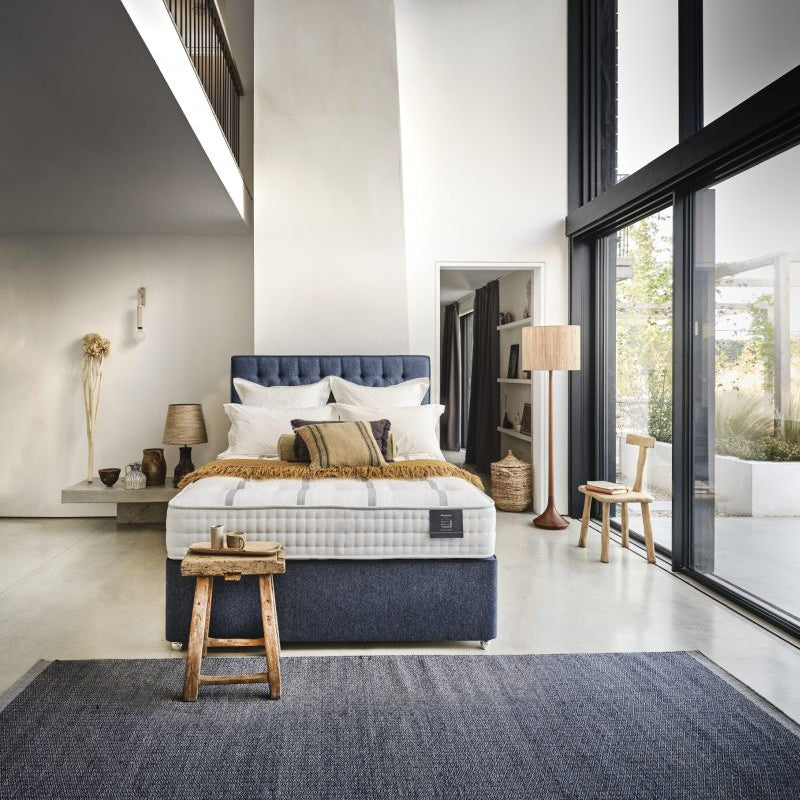Bed with white mattress, blue headboard, and pillows on a white background