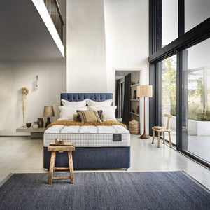 Bed with white mattress, blue headboard, and pillows on a white background