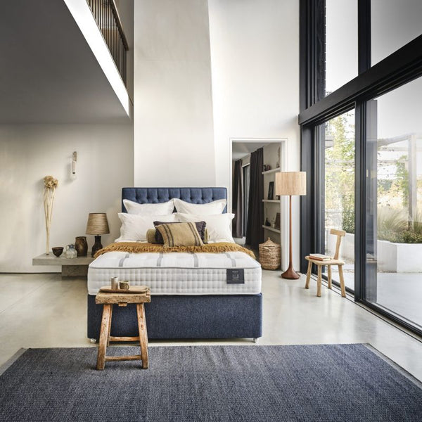 Bed with white mattress, blue headboard, and pillows on a white background