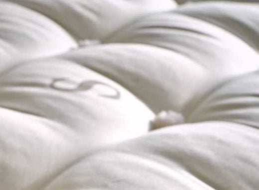 Close-up of a white quilted surface with visible branding.