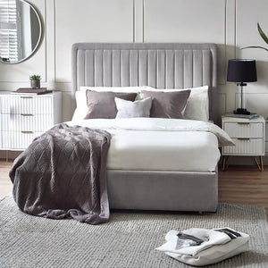 Neatly made bed with gray headboard and bedding in a modern bedroom.