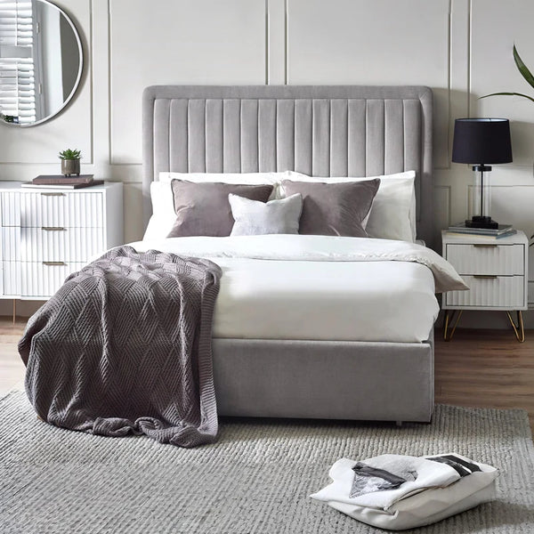 Neatly made bed with gray headboard and bedding in a modern bedroom.