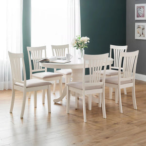 Dining room with white table and chairs on a wooden floor.