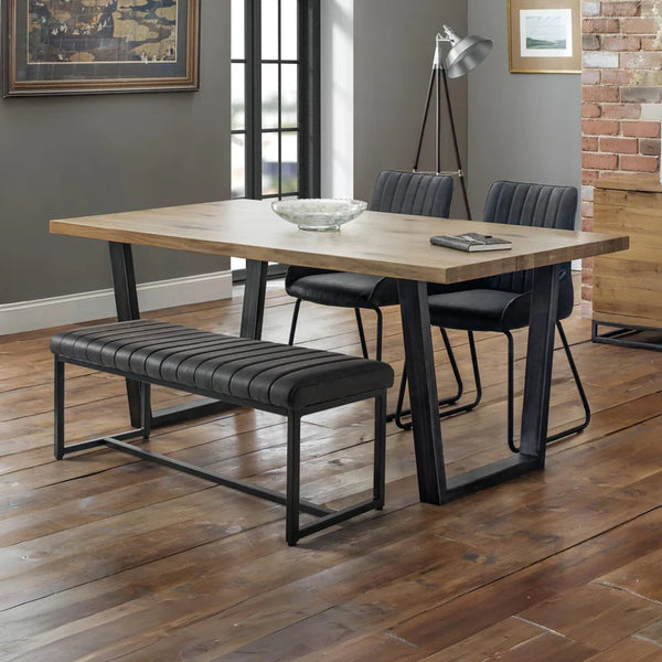 Dining area with wooden table, black chairs, and bench on a wooden floor.