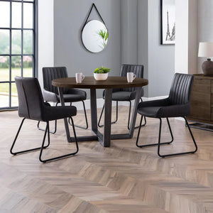 Dining room with a round wooden table and black chairs on a herringbone wood floor.